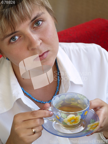 Image of Young woman in blue necklace drinking tea