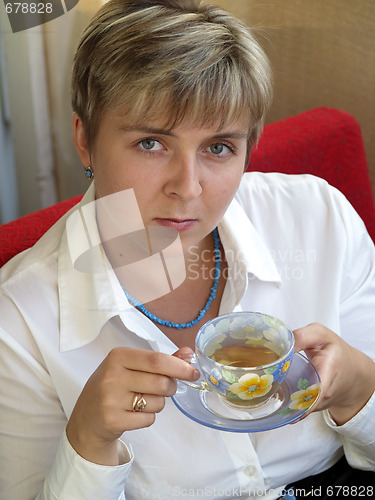 Image of Young woman in blue necklace drinking tea