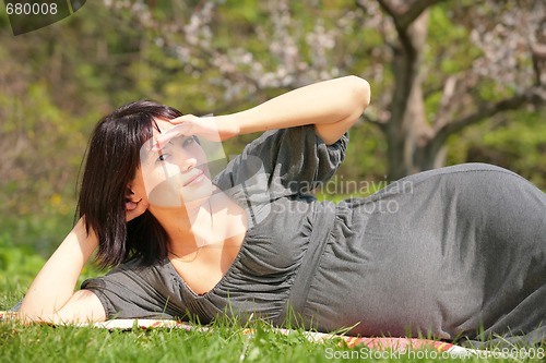 Image of expectant mother reposes in town park