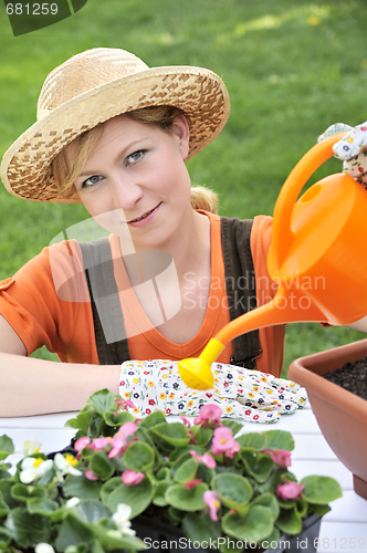 Image of Young woman watering flowers