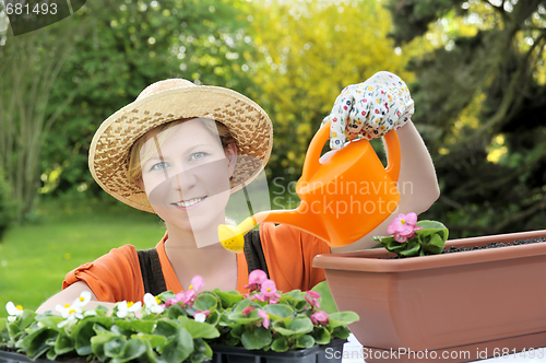 Image of Young woman watering flowers