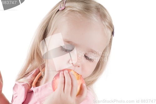 Image of Little girl eating peach in studio