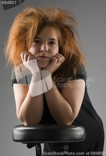 Image of beautiful girl leaned one's elbows on a chair