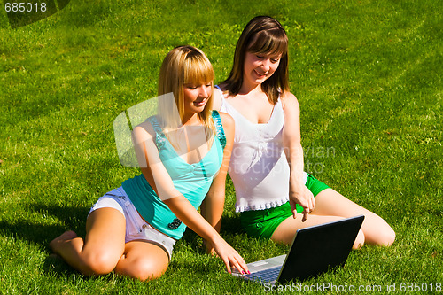 Image of Two young girls on the grass with notebook