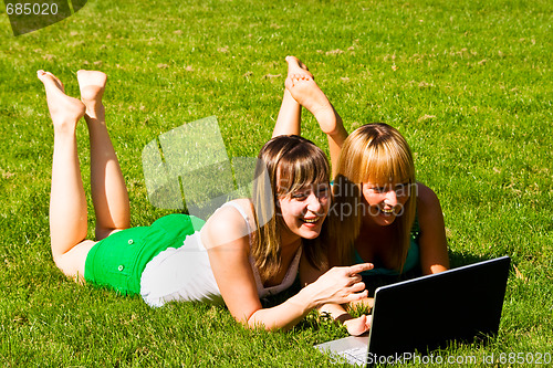 Image of Two young girls on the grass with notebook