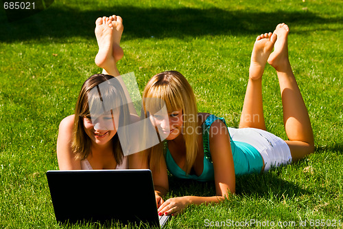 Image of Two young girls on the grass with notebook