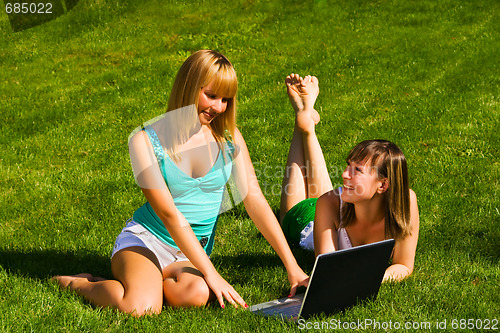 Image of Two young girls on the grass with notebook