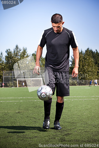 Image of Hispanic soccer or football player kicking a ball