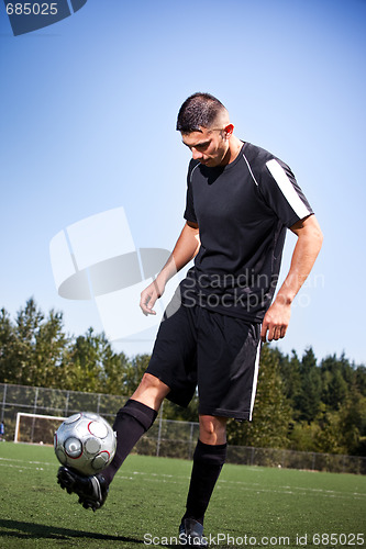 Image of Hispanic soccer or football player kicking a ball