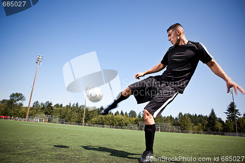 Image of Hispanic soccer or football player kicking a ball