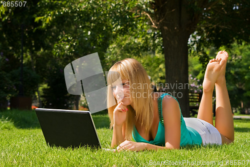 Image of Young thoughtful girl on the grass with notebook