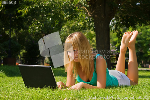 Image of Young smiling girl on the grass with notebook