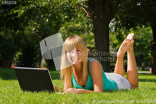 Image of Young smiling girl on the grass with notebook