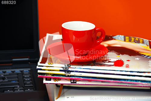 Image of Red cup on magazines and notebook over red