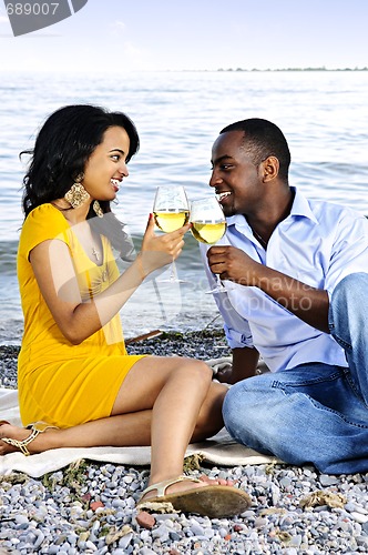 Image of Happy couple having wine on beach