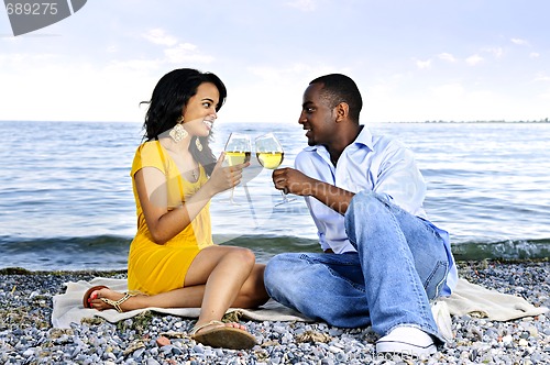 Image of Happy couple having wine on beach