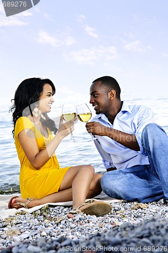 Image of Happy couple having wine on beach