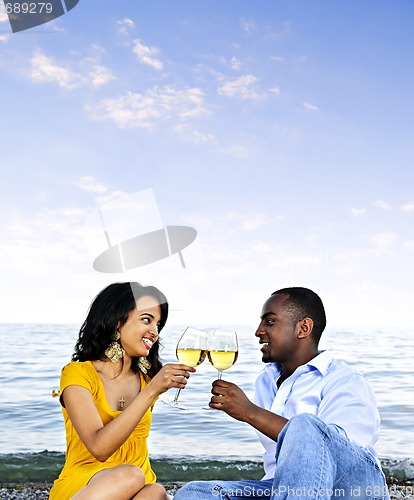 Image of Happy couple having wine on beach