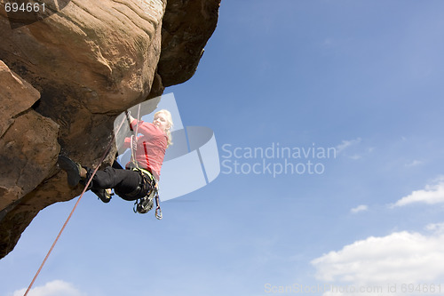 Image of Young woman climbing a rock