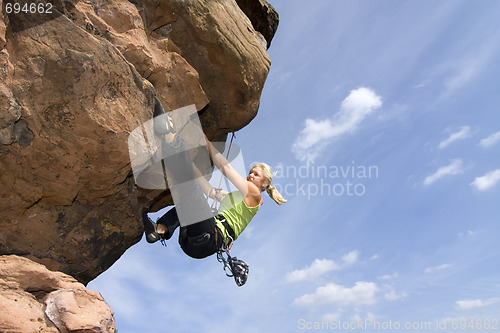 Image of Young woman climbig a rock