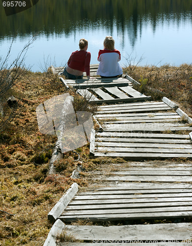 Image of Two girls sit on pier