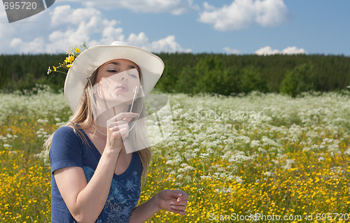 Image of Beautiful girl blows on dandelion in white hat