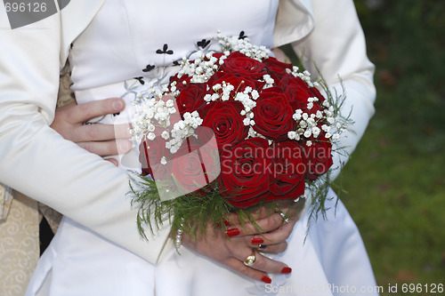 Image of Bride and groom holding hands, bride holding bouquet