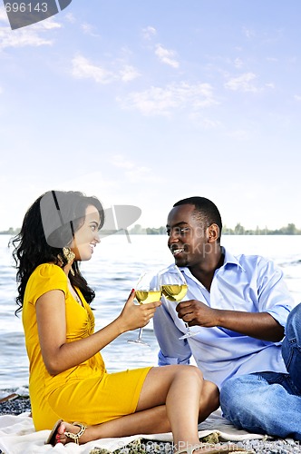 Image of Happy couple having wine on beach
