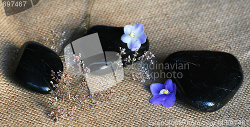 Image of Spa stones with lilac flowers on sackcloth background