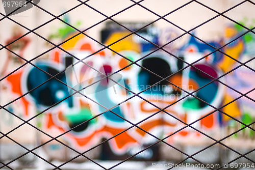 Image of abstract graffiti through metal bars fence