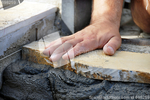 Image of Worker hand on flagstone