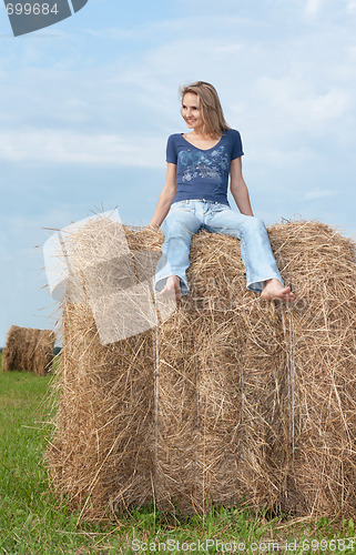 Image of Beautiful girl sits on hay