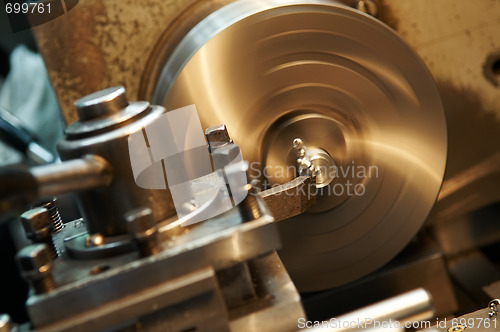 Image of facing metal blank by cutter on lathe