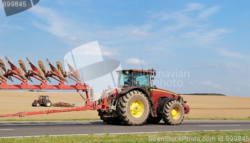 Image of Tractor moving plough on the road