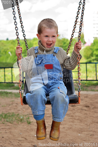 Image of boy is playng on the swings