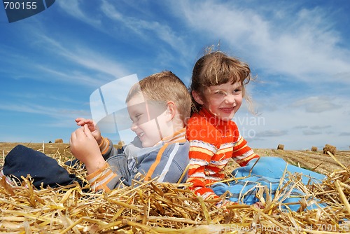 Image of smiling boy and girl in straw outdoors