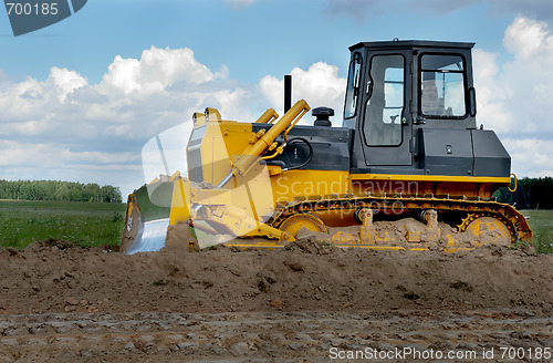 Image of bulldozer in fields over blue cloudy sky