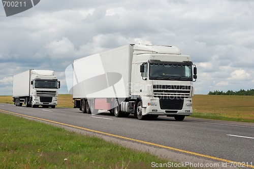 Image of couple of white trucks on highway