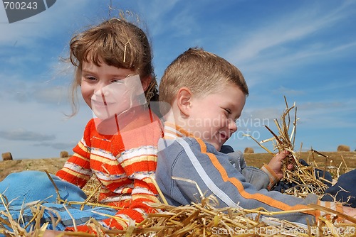 Image of Two smiling children in straw outdoors