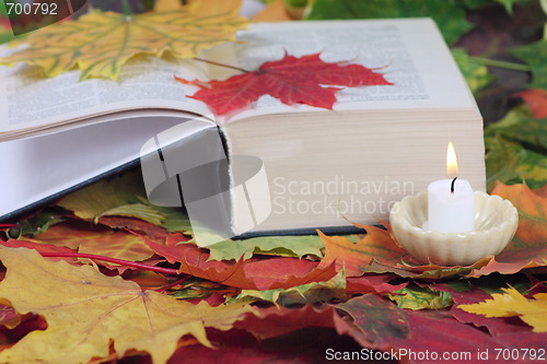 Image of Candle and the book on autumn leaves