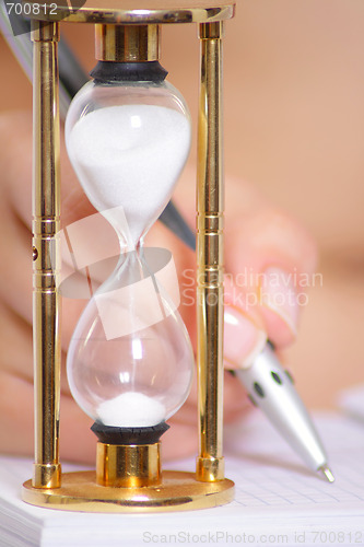 Image of Female hand with pen and sand clock