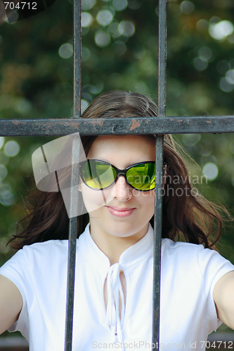 Image of The young woman in sun glasses behind an iron protection
