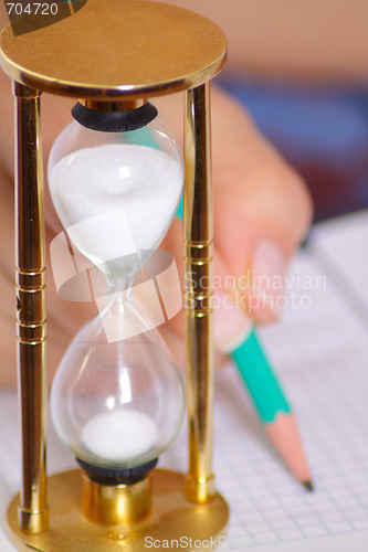 Image of Sand-glass with female hand holding pencil