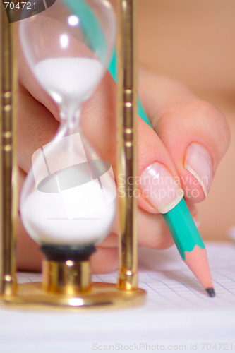 Image of Female hand with a pencil and a sand clock