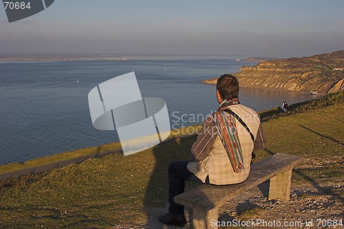 Image of Man sitting on bench overlooking sea