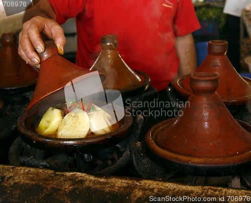 Image of Market cook holding a cover of a tajine dish (traditional casser
