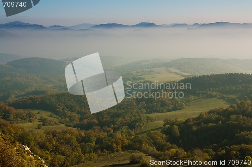 Image of green valley with mountains in fog