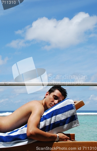 Image of Young man sunbathing in a Maldives resort room