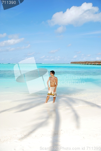 Image of Young man standing on a tropical beach in Maldives