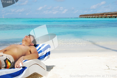 Image of Young man sunbathing in a Maldivian Island beach